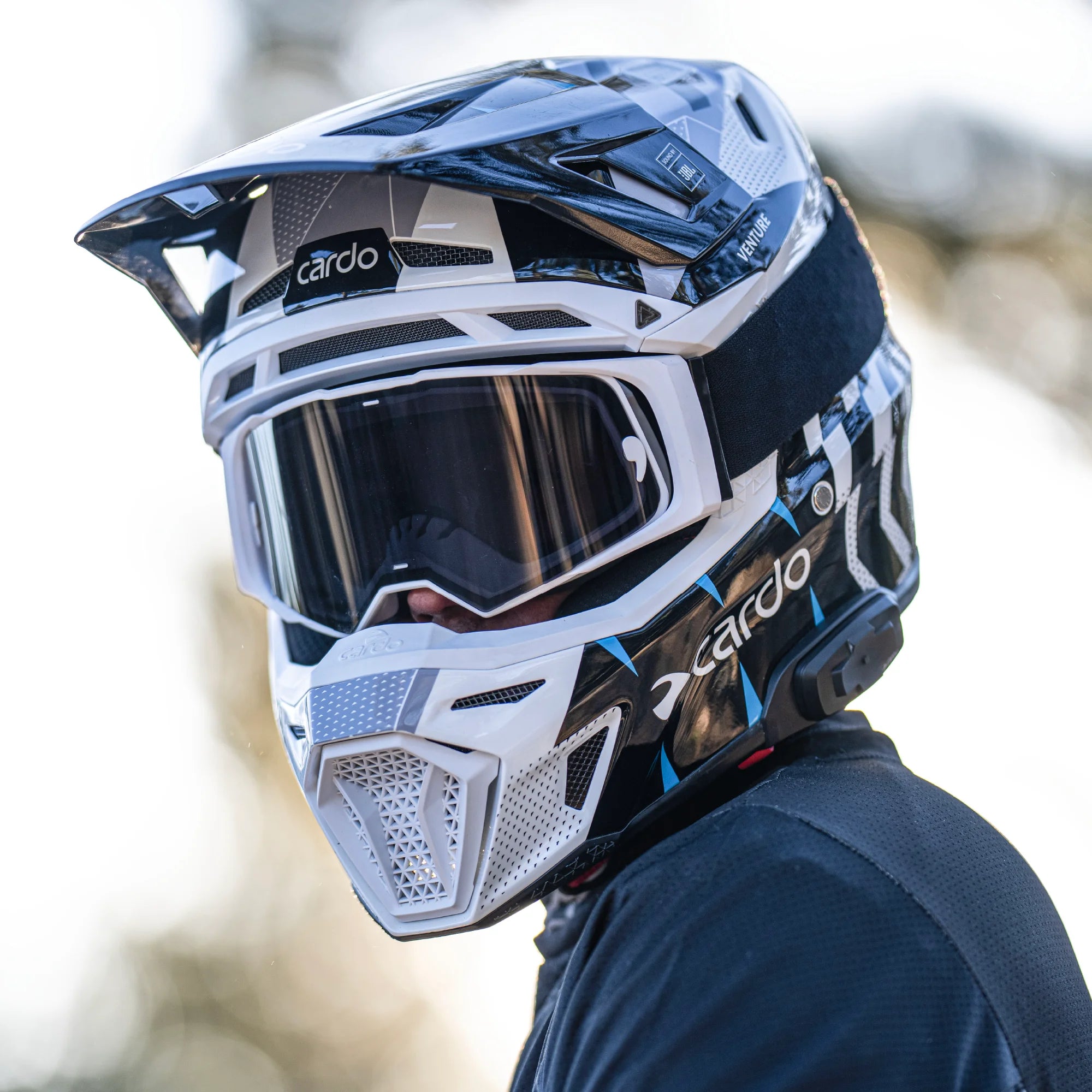 Cardo Venture off-road motorcycle helmet with goggles, lifestyle shot worn by male rider front profile