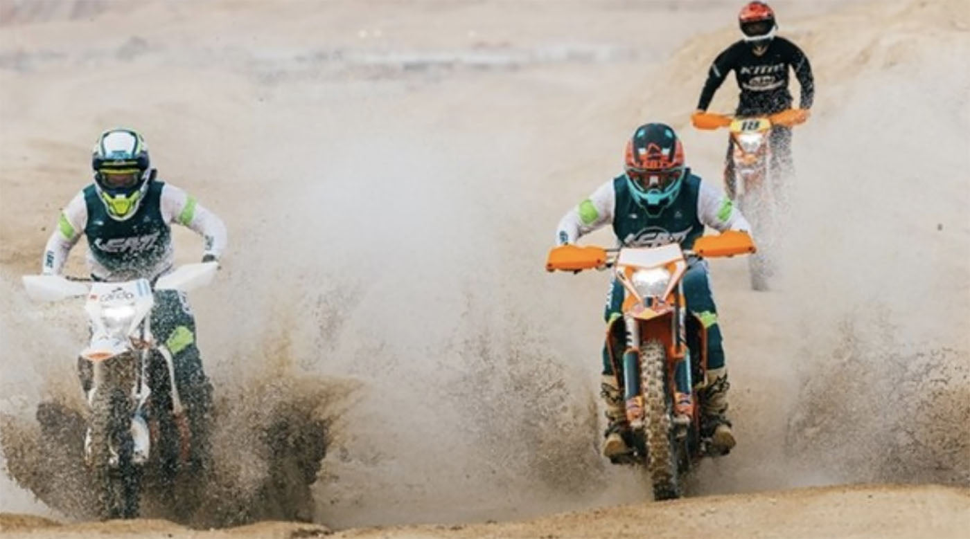 trio dirt bikers ride in desert