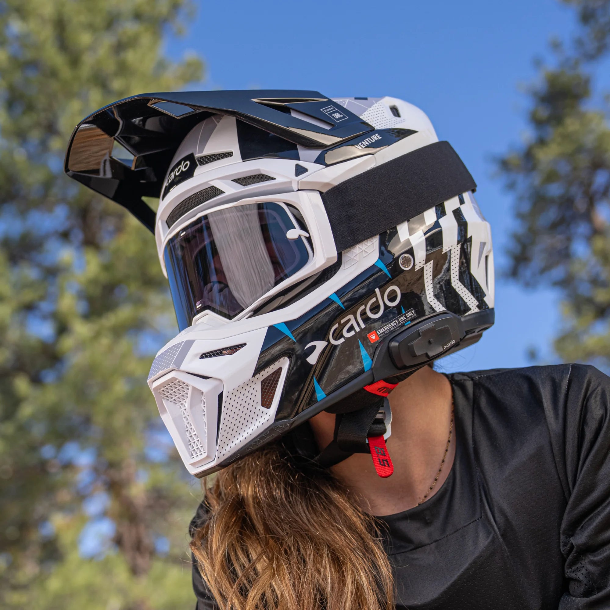 Cardo Venture off-road motorcycle helmet, lifestyle shot worn by female rider with comms unit attached