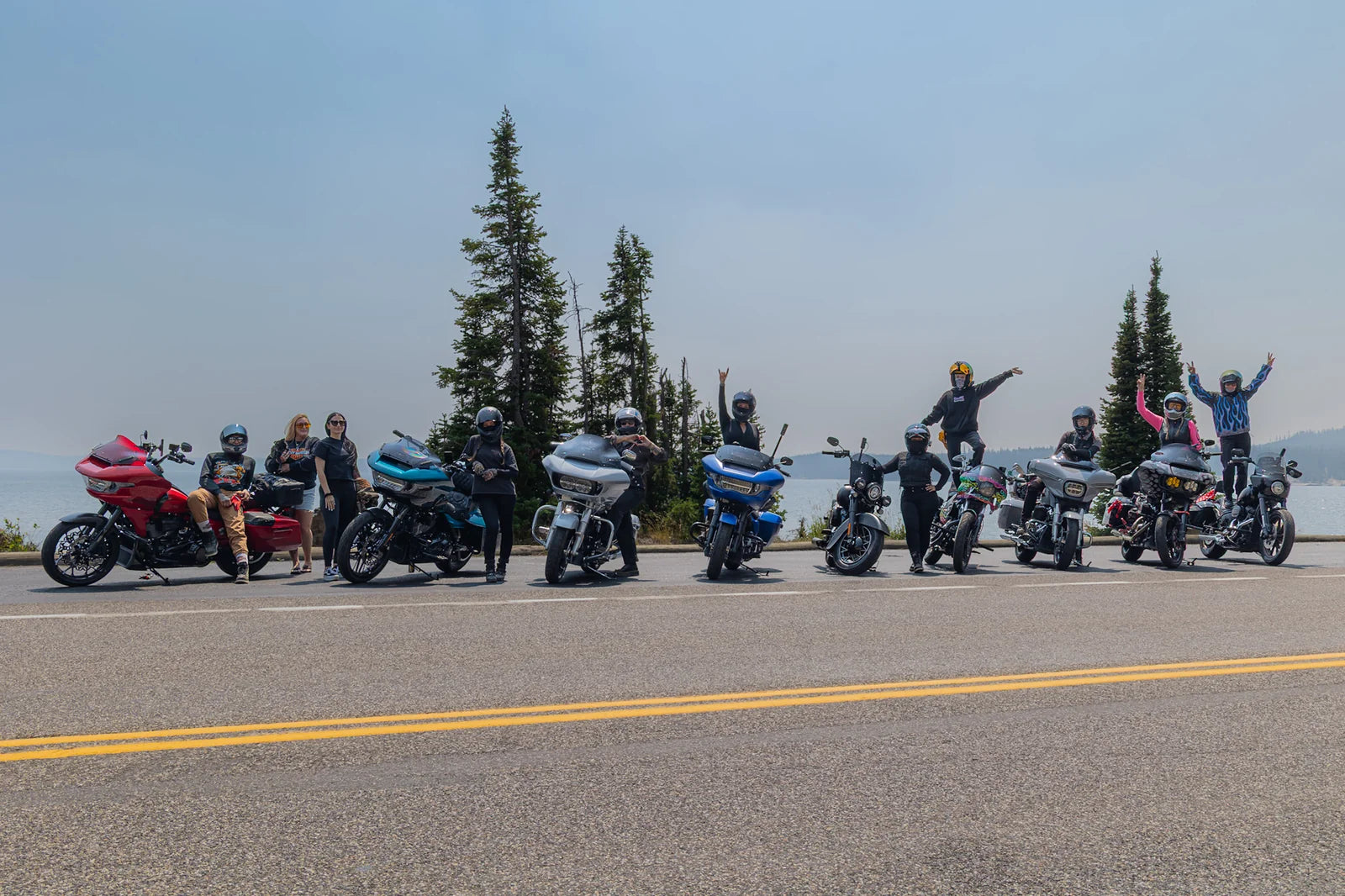 A group of women riders with their motorcycles beside a mountain road.