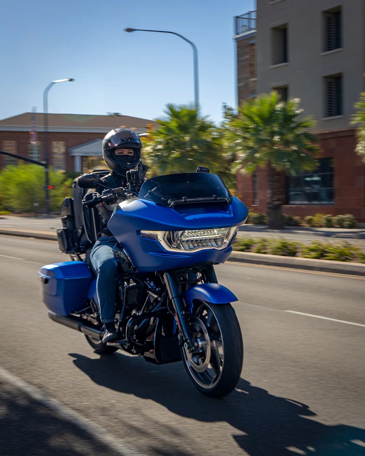 A helmeted rider travelling on a blue touring motorcycle.